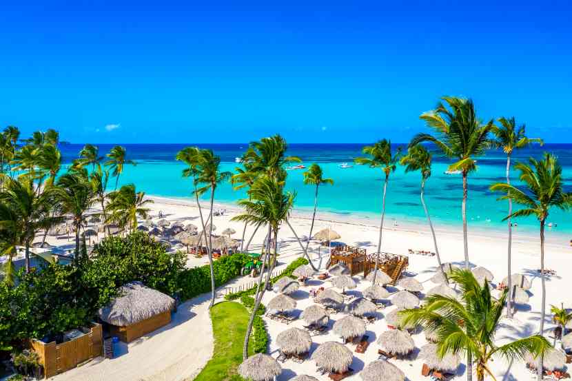 Aerial-view-caribbean-tropical-beach-with-straw-umbrellas-palms-boats-bavaro-punta-cana-dominican-republic - travel and tour world