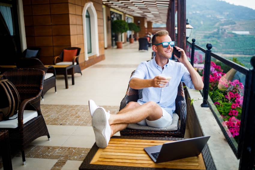 Freelancer-concept-successful-young-man-businessman-working-laptop-computer-sitting-terrace-drinking-coffee-talking-phone - travel and tour world