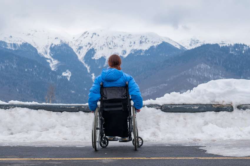 Rear-view-man-sitting-snow-covered-mountain - travel and tour world