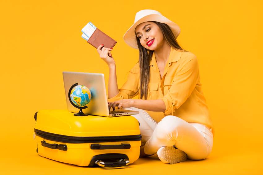 Woman-planning-trip-laptop-while-holding-plane-tickets-passport - travel and tour world