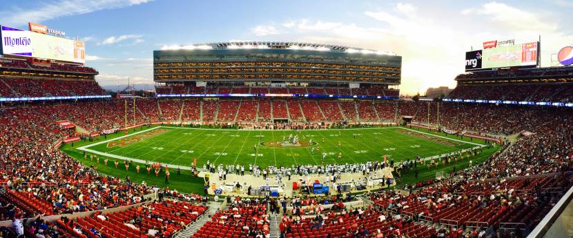 An nfl stadium filled with passionate fans, showcasing the impact of football on tourism, with tourists filling city streets and local hotels during game days.