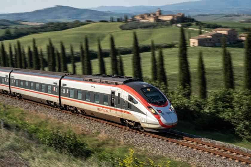 Italy high-speed train in scenic countryside - travel and tour world Modern italy train traveling through lush green landscape with cypress trees.