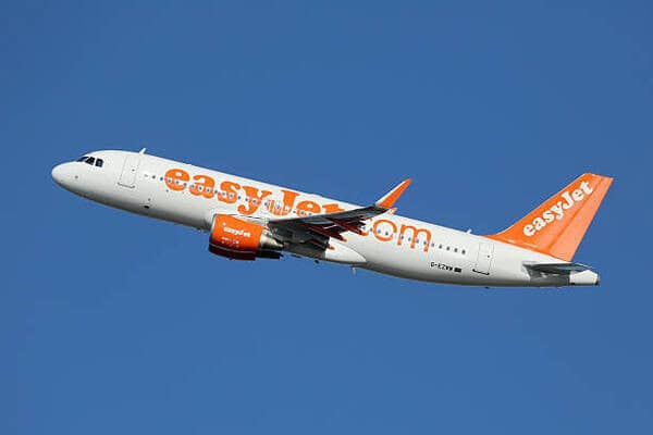 Travel and tour world - travel and tour world Easyjet airplane in flight over clear blue sky.