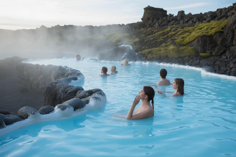 Relaxing hot spring pool surrounded by volcanic landscape and lush greenery.