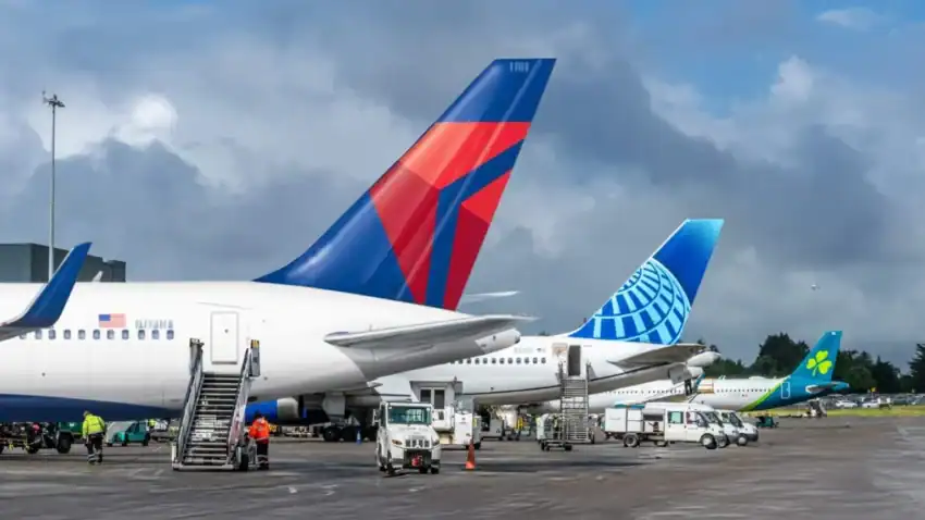 Airport scene with multiple airplanes and ground crew activities.