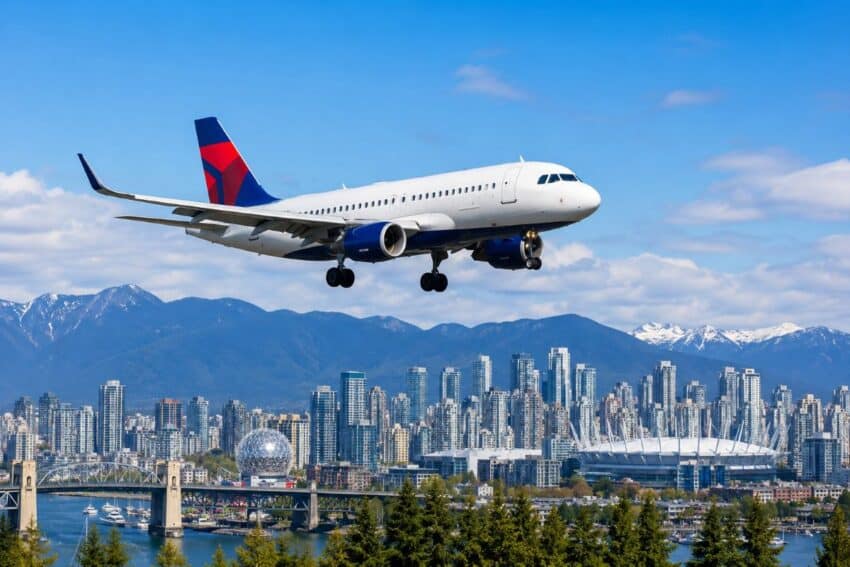 - travel and tour world Delta airlines airplane flying over vancouver skyline with mountains in backgrou.