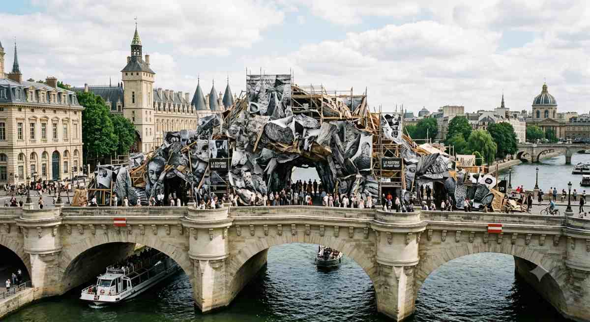 The installation la caverne du pont neuf by artist jr, showing a massive immersive structure transforming the historic stone architecture of the pont neuf bridge in paris.