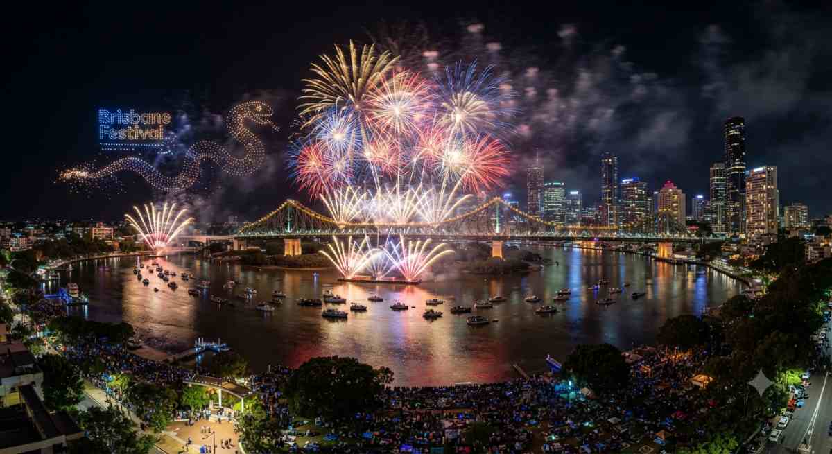 Brisbane festival - travel and tour world A dazzling aerial display of fireworks and pyrotechnic drones illuminating the night sky over the brisbane river, showcasing the vibrant skyline during the brisbane festival.
