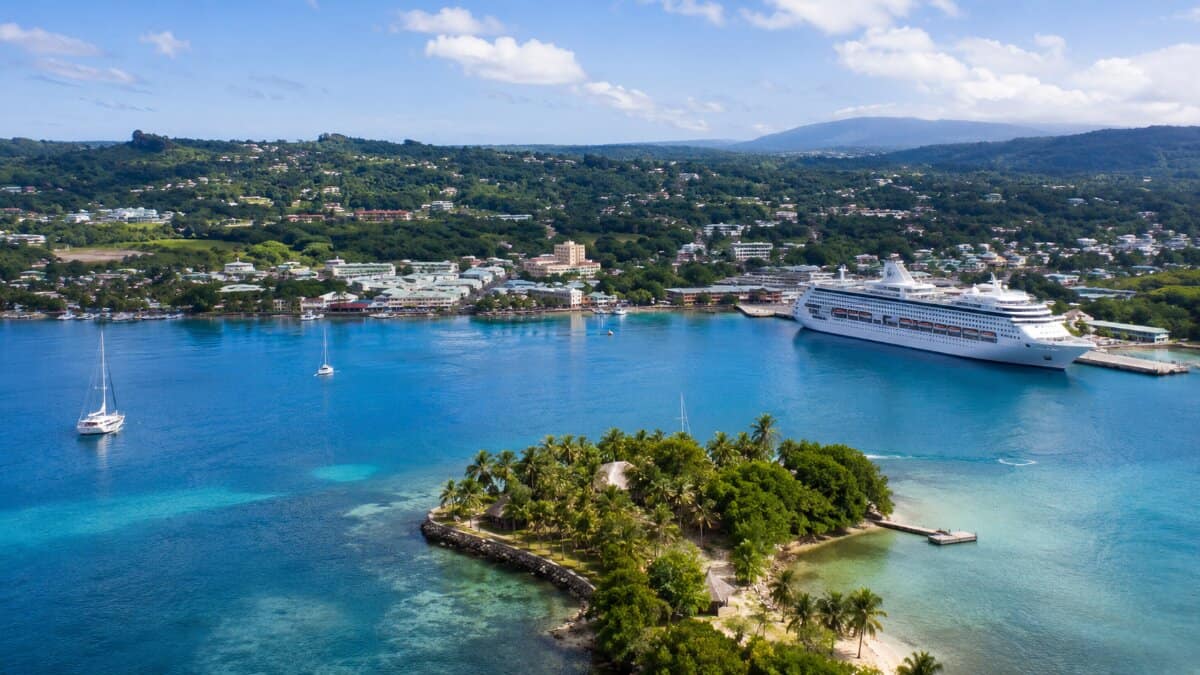 Vanuatu cruise tourism connects port vila and outer islands - travel and tour world Aerial editorial view of a cruise ship docked at port vila, vanuatu, beside turquoise waters, a tropical island and coastal communities.