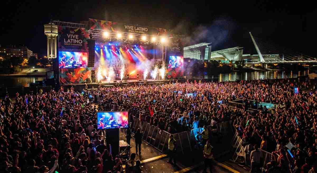 Vive latino spain - travel and tour world A vibrant, atmospheric view of the vive latino festival stage in zaragoza, featuring illuminated lighting, large crowds, and the iconic festival branding during a summer night.