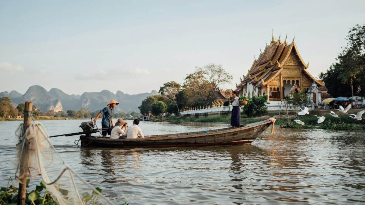 People ride boat past temple in laos