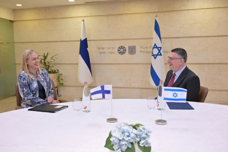 Finnish and israeli officials meet beside finland and israel flags during bilateral talks.