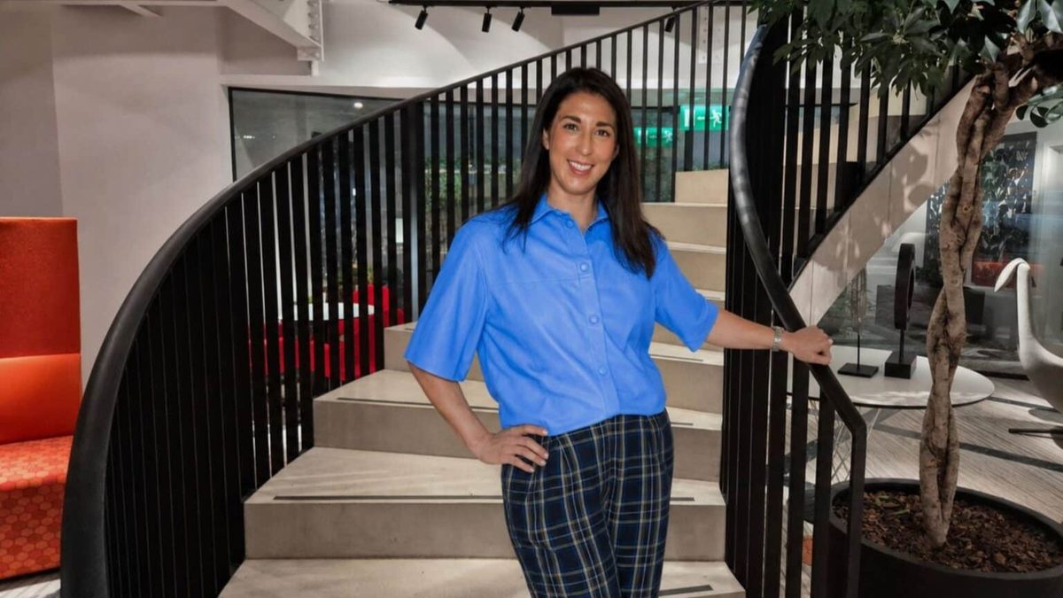 Erin johnson, newly appointed group marketing director at unforgettable travel company, standing on a staircase in a modern office setting.