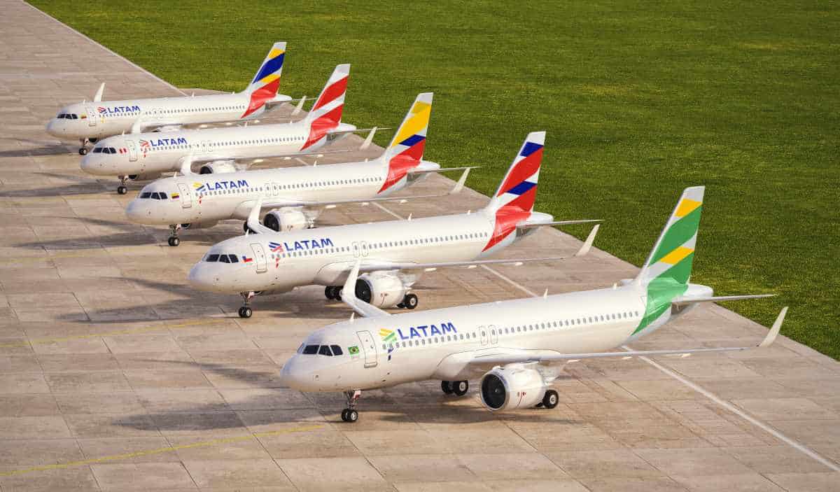 An airbus a320 aircraft operated by latam parked on a tarmac with scenic andean mountains rising in the background of cusco.