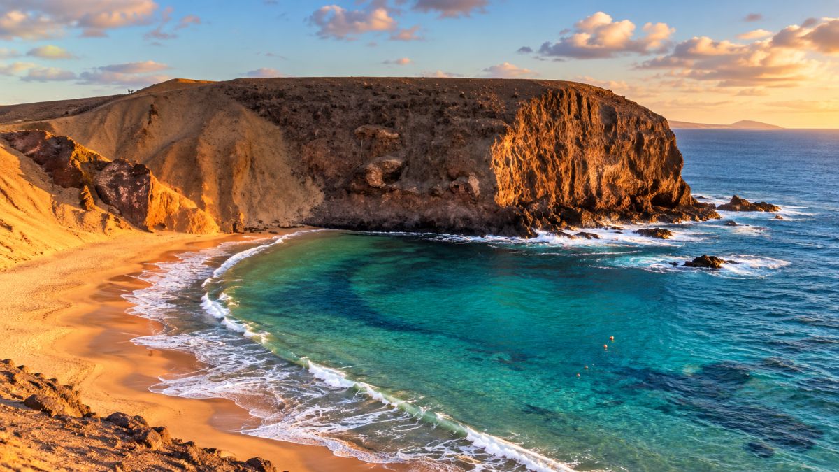 Scenic canary islands coastline with golden beach, atlantic ocean, volcanic mountains and bright winter sunshine in december