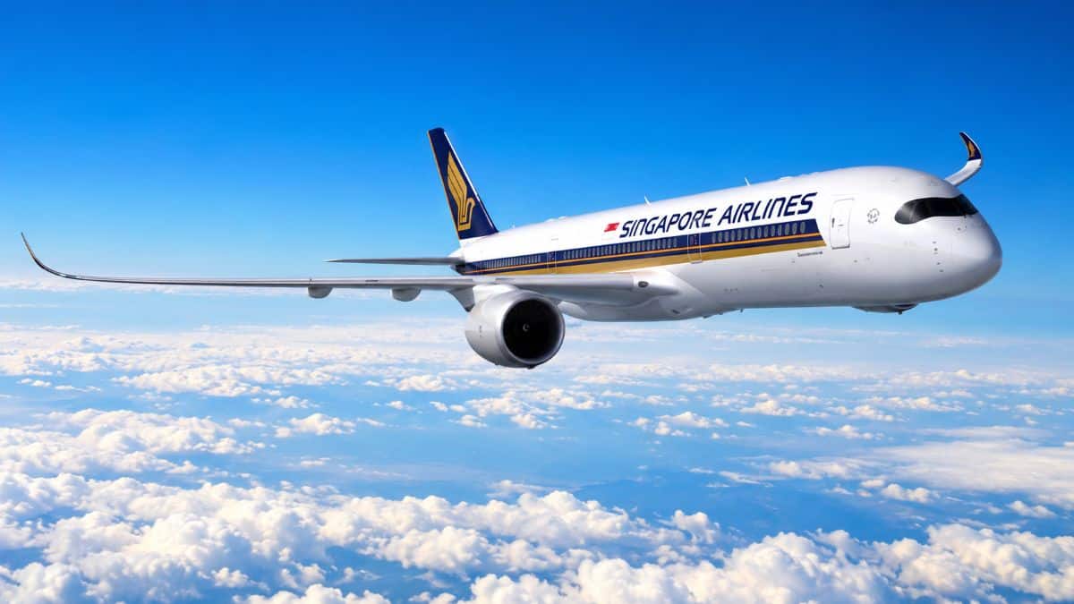 Singapore airlines passenger aircraft flying above a sea of clouds under a bright blue sky