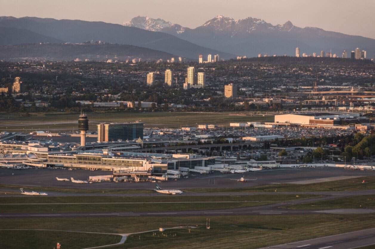 Aircraft and runways at vancouver international airport with mountains beyond the terminal.
