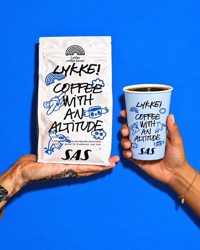 Scandinavian airlines - travel and tour world Hands holding lykke coffee farms coffee packaging and an sas-branded coffee cup against a bright blue background, showcasing the new inflight coffee offering.