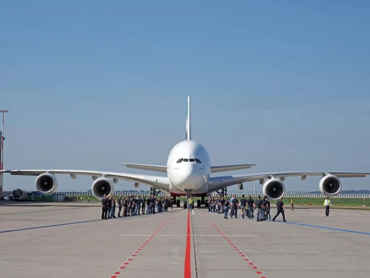 Qantas airbus a380 outside an aircraft maintenance hangar with aviation engineers and ground vehicles
