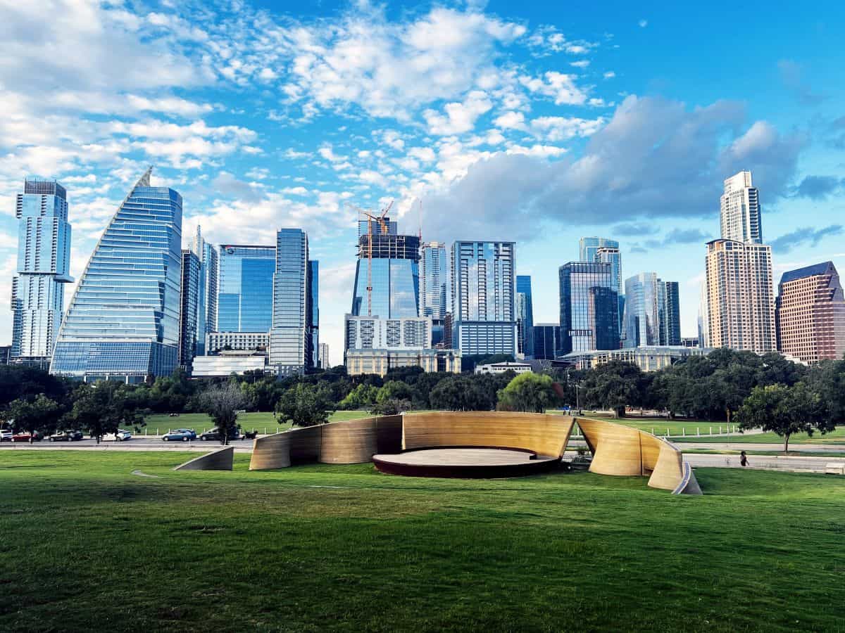 Austin tourism - travel and tour world Austin, texas skyline overlooking a green urban park with modern skyscrapers under a bright blue sky.