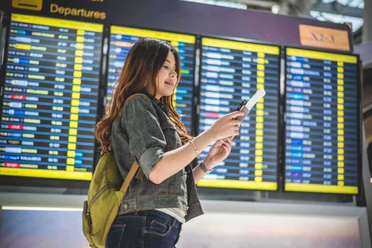 International student looking at her phone inside an airport terminal.