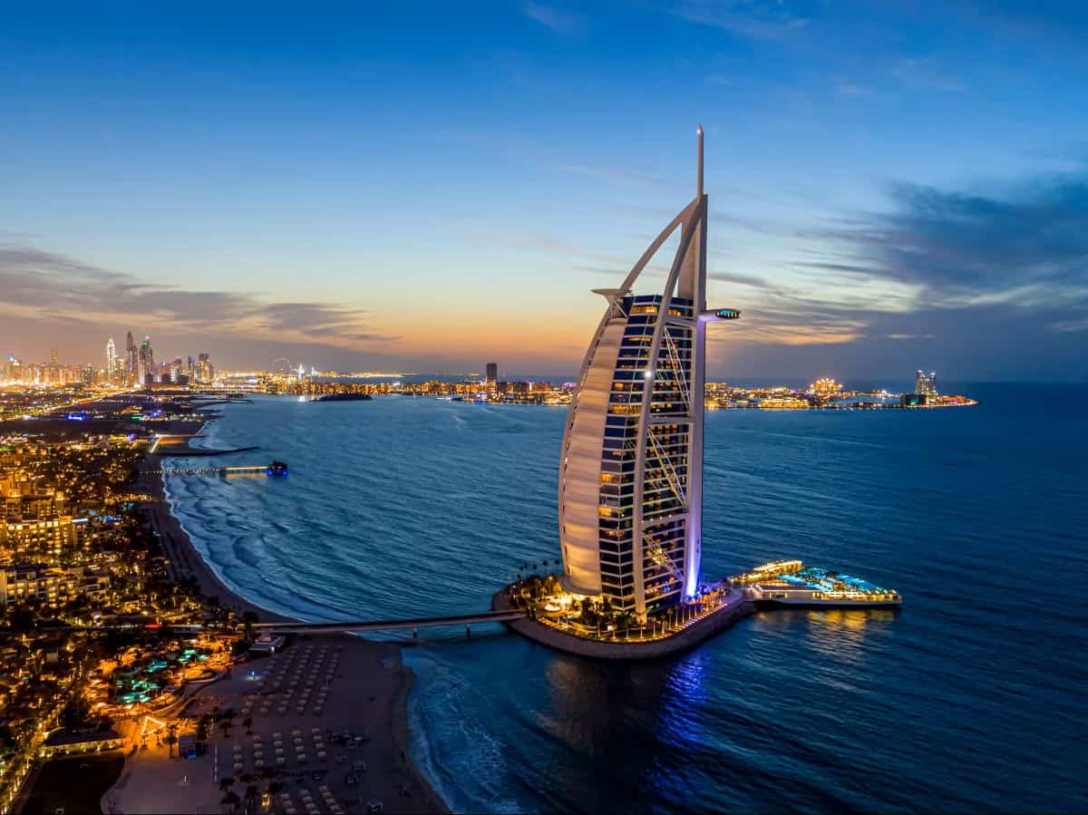 Dubai tourism - travel and tour world Dubai’s burj al arab hotel overlooking the illuminated coastline at sunset.
