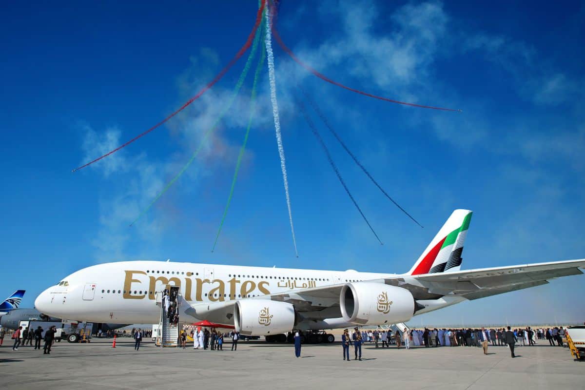 Emirates a380 aircraft with colourful smoke trails overhead