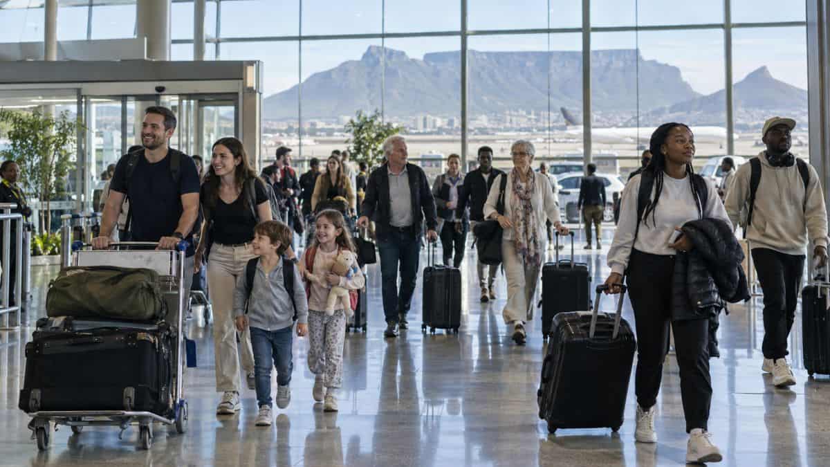 Family arrivals beneath mountain skies - travel and tour world A south african guest-house owner checks bookings as international tourists arrive with luggage.