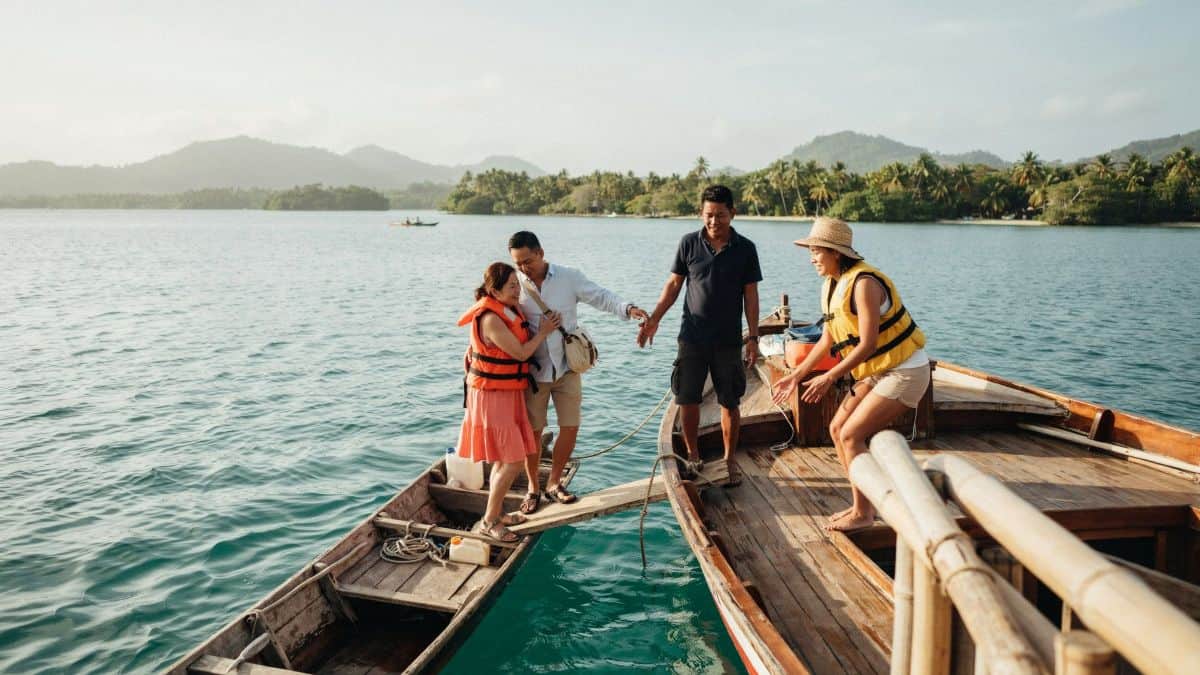 Travellers wearing life jackets board an island transfer boat in fiji.