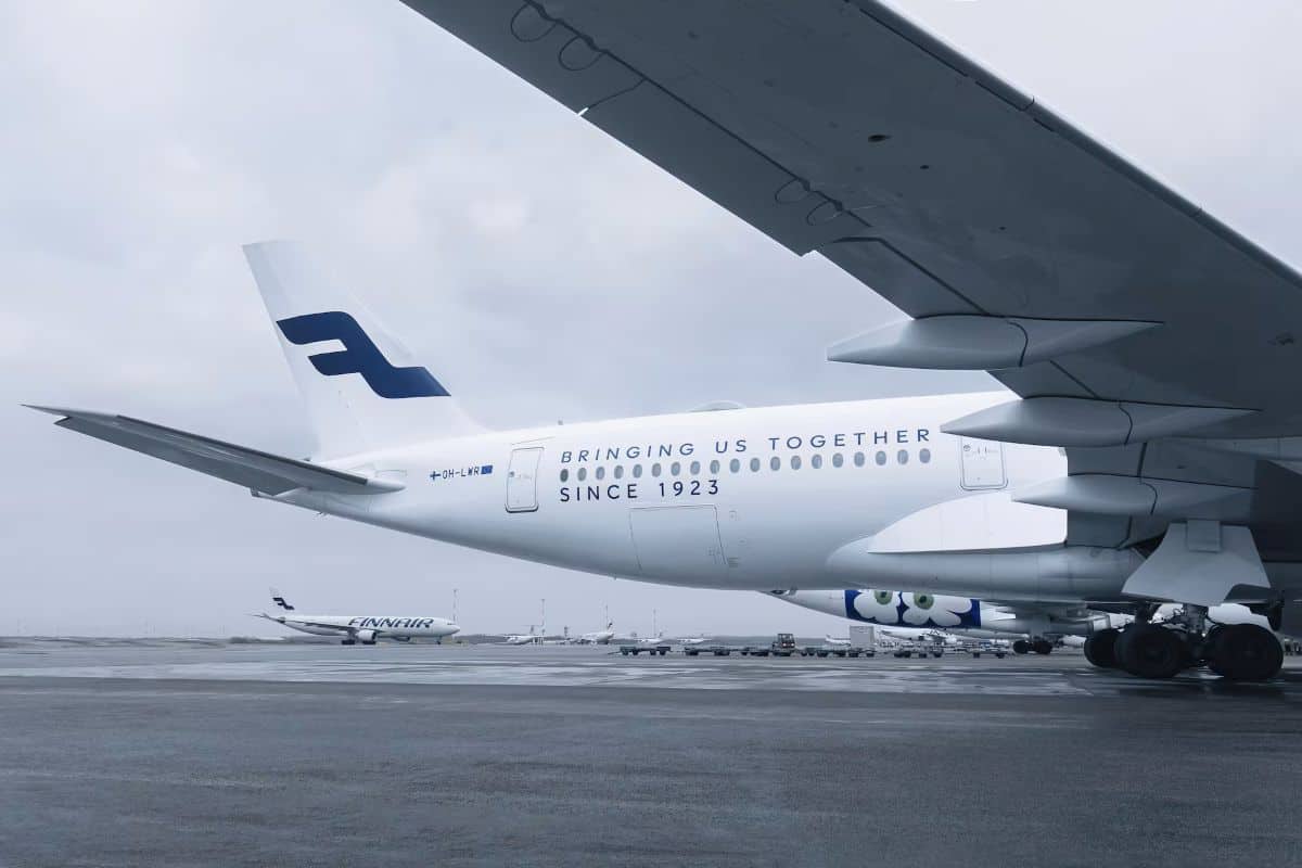 Finnair - travel and tour world Finnair aircraft parked on an airport apron under an overcast sky, featuring the airline’s centenary livery, with another finnair plane in the background.