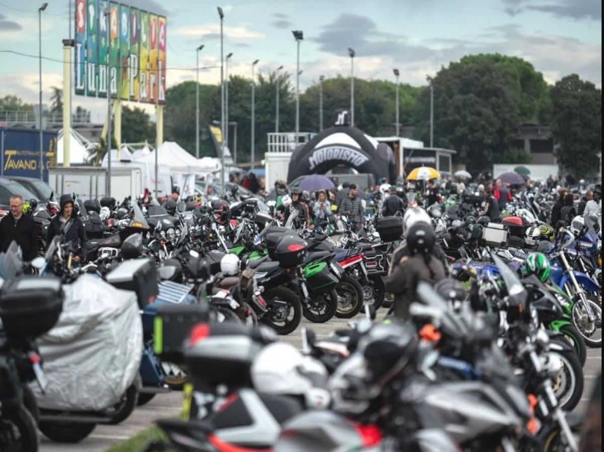 A large gathering of motorcycles parked densely together at italian bike week in lignano sabbiadoro, with visitors walking through the event grounds near a 'luna park' sign in the background.