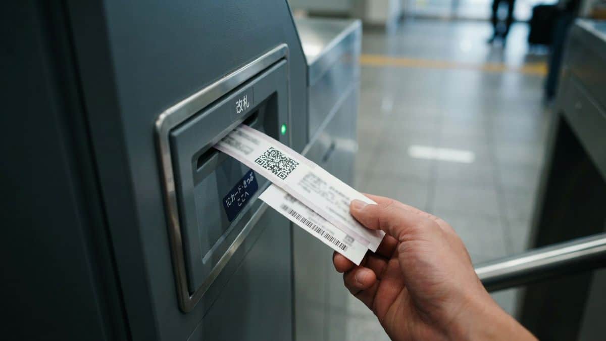 Japan is now set to see new paper qr tickets as seven operators change rail travel from spring 2027 - travel and tour world A hand holds paper tickets bearing qr and barcodes at an automatic railway ticket gate in japan.