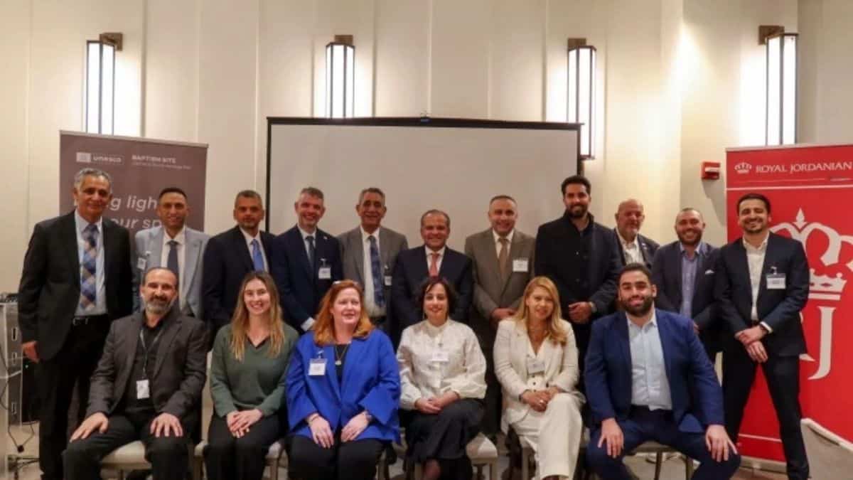 Jordan - travel and tour world A group portrait of jordan tourism board delegates, destination management representatives, and travel industry partners posing together in front of promotional banners for the unesco baptism site and royal jordanian during the 2026 north american promotional roadshow launch event.