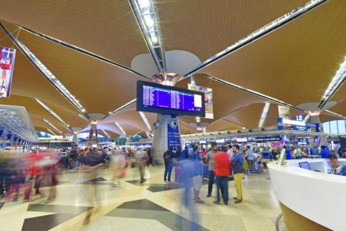 Kl airport - travel and tour world Kuala lumpur international airport terminal with flight information displays and busy passenger check-in areas.