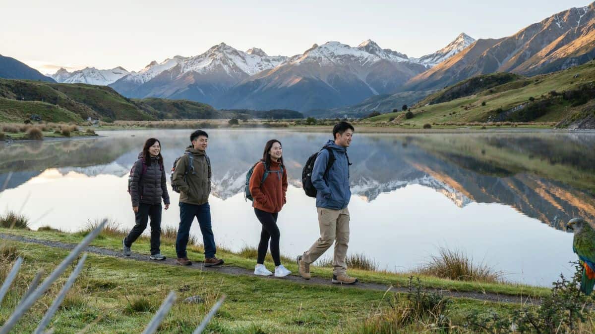 New zealand tourism - travel and tour world Asian visitors walk beside a clear alpine lake in new zealand.