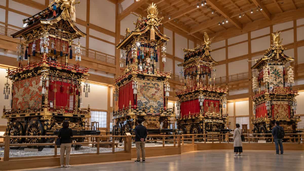 Visitors admire ornate wooden festival floats inside a takayama exhibition hall in gifu, japan.