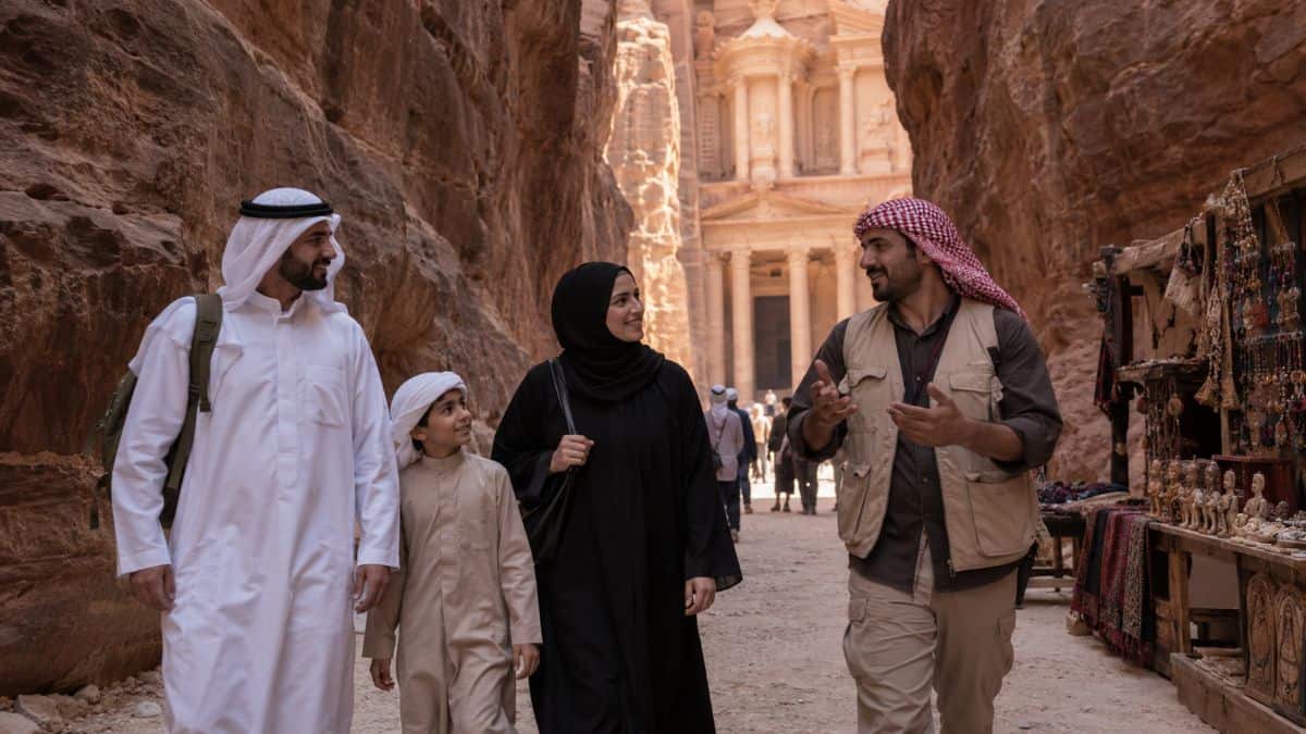Petra treasury through the siq - travel and tour world A gulf family walks with a local guide through petra’s rose-red siq towards the treasury in jordan, passing a small stall selling traditional handicrafts.