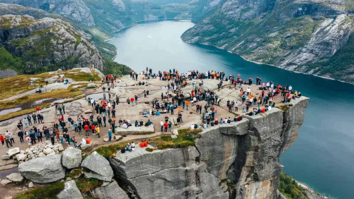 Preikestolen cliff overlooking lysefjord in norway with hikers on the trail.