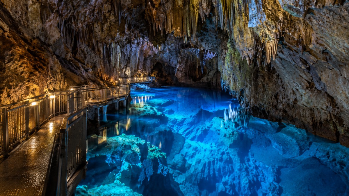 Ryusendo caves glowing underground lake - travel and tour world Illuminated walkway inside ryusendo cave