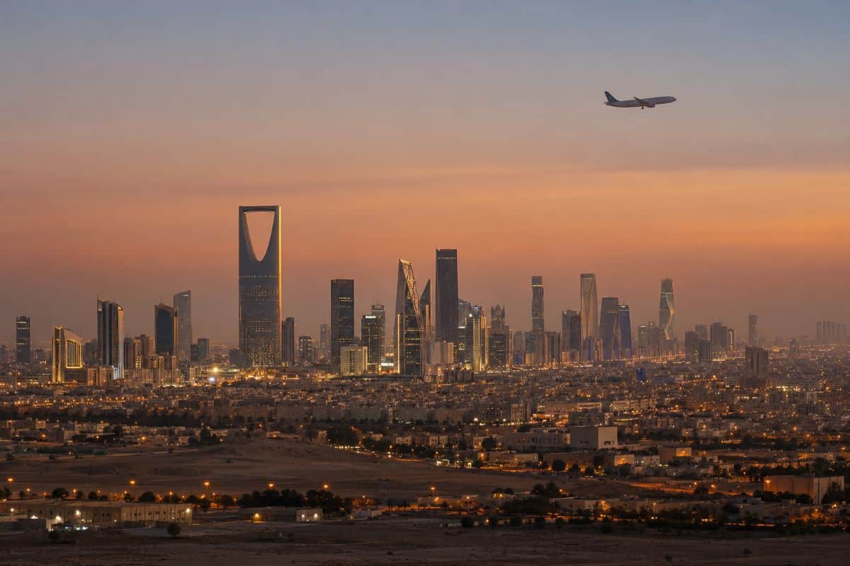 Riyadh skyline and kingdom centre at dusk with a passenger aircraft overhead
