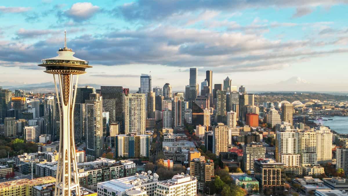 Seattle - travel and tour world Aerial view of the seattle skyline featuring the space needle and downtown skyscrapers beneath a partly cloudy sky.