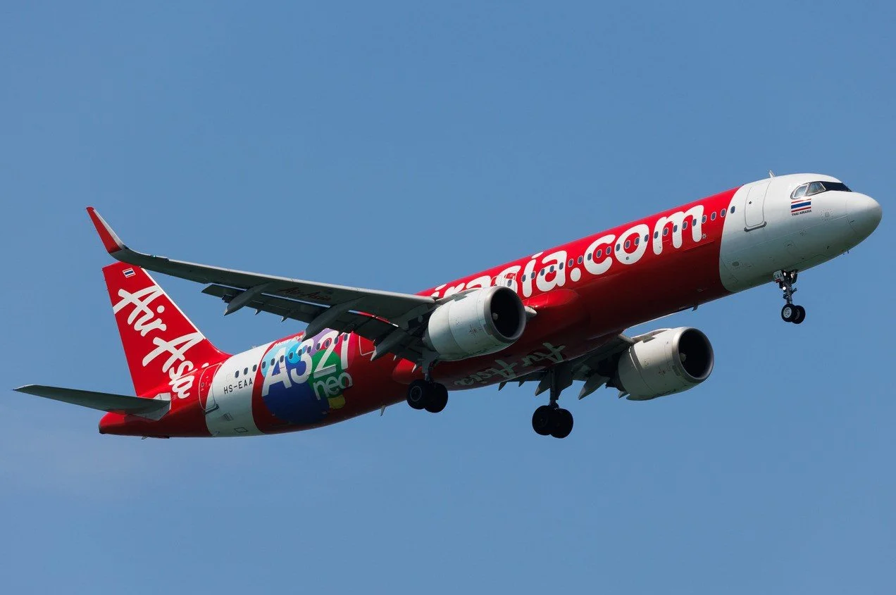 Airasia airbus a321neo aircraft displaying the airline's distinctive red-and-white branding at an international airport.
