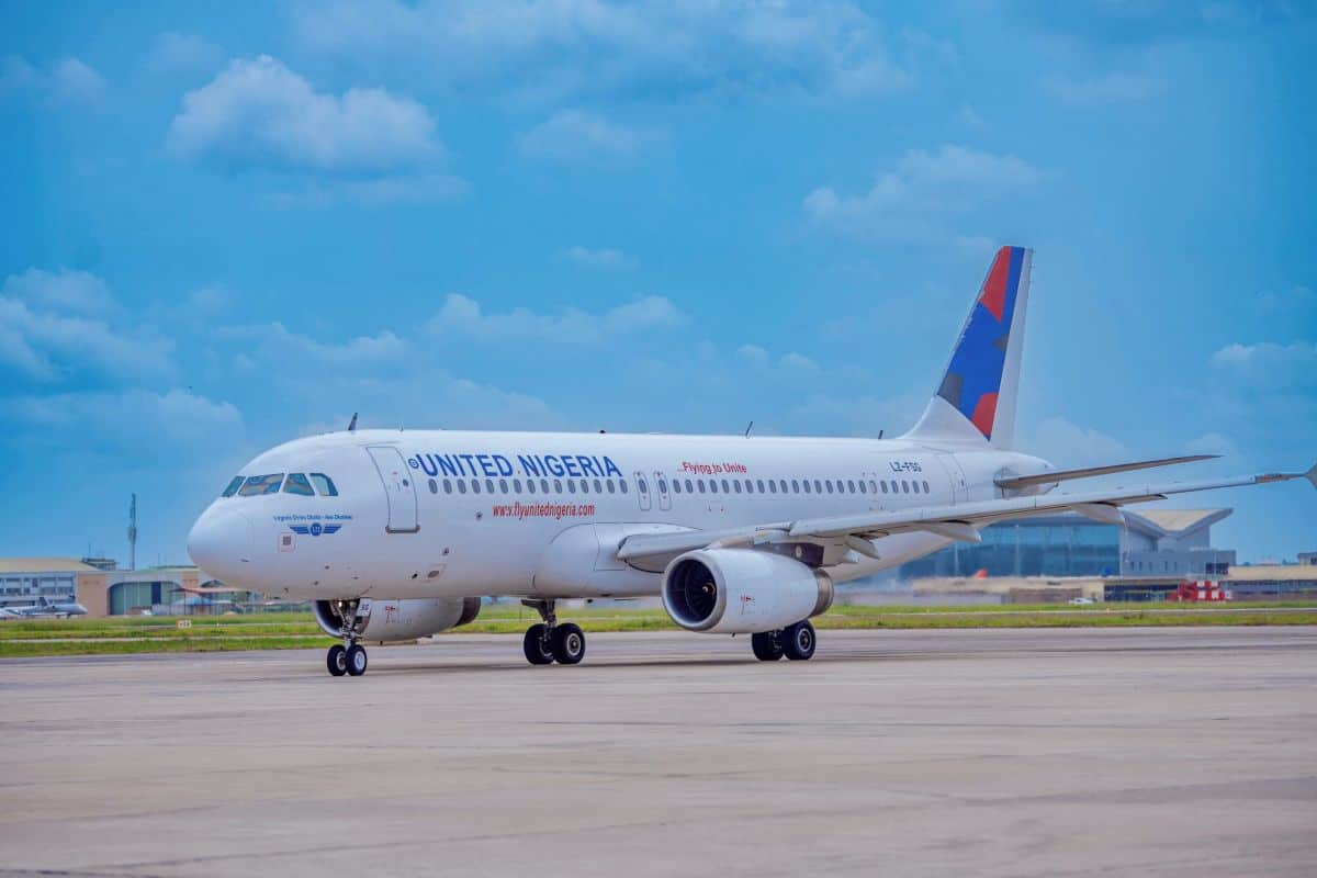 United nigeria airlines is now seeking ₦20 billion as it aims to expand and unlock better travel connections - travel and tour world United nigeria airlines aircraft on an airport apron beneath a blue sky, with airport buildings in the background