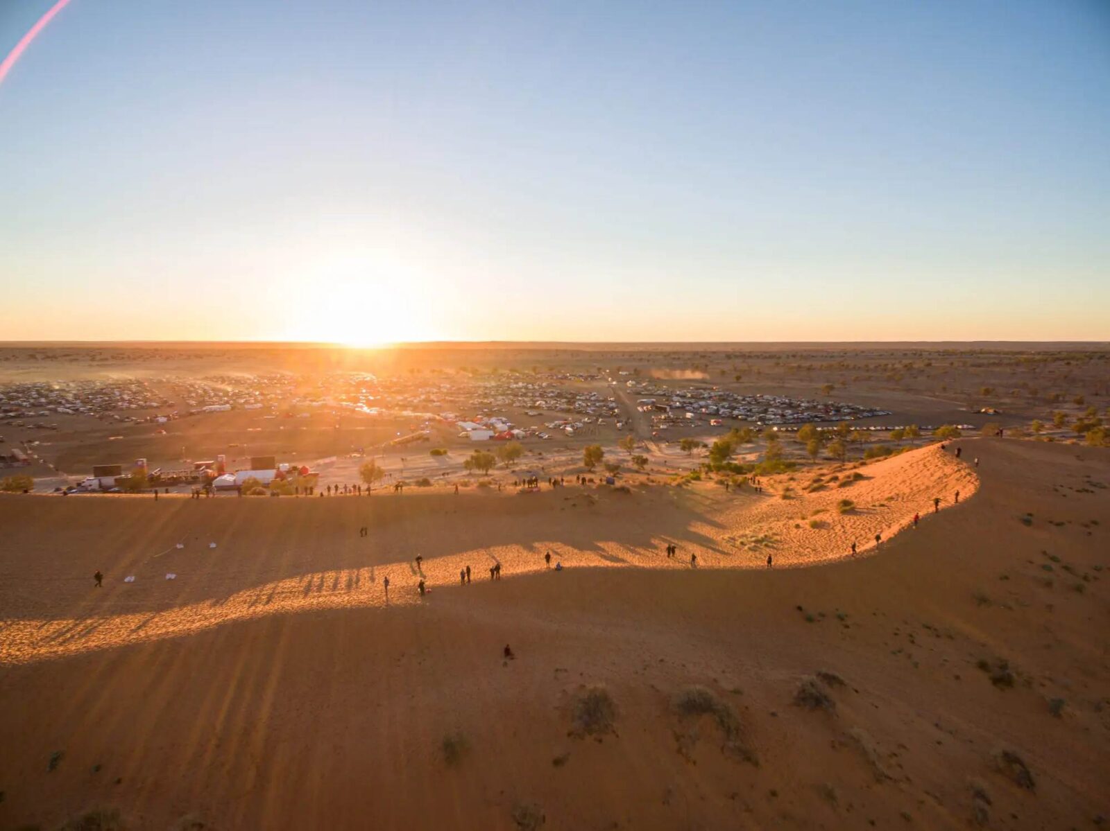 Big red bash caravans and campsites stretching across the desert near birdsville at sunset.