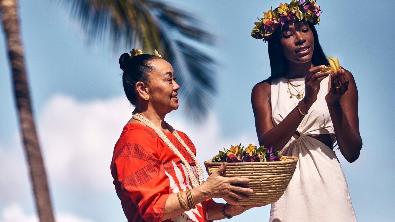 Festivals-of-aloha-2026-hawaiian-lei-making-four-seasons-maui - travel and tour world Two women handling tropical flowers for hawaiian lei making, with a woven basket and floral crown, reflecting maui's cultural traditions.