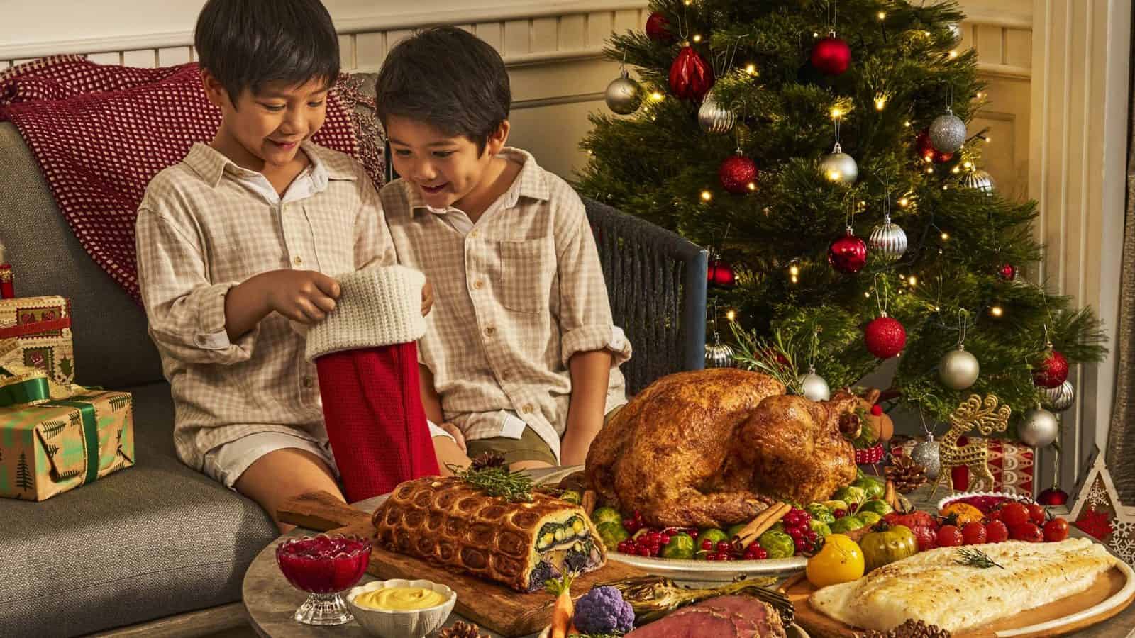 Four-seasons-hotel-singapore-christmas-2026-family-festive-dining - travel and tour world Children enjoying a festive christmas feast with roasted turkey and holiday decorations.