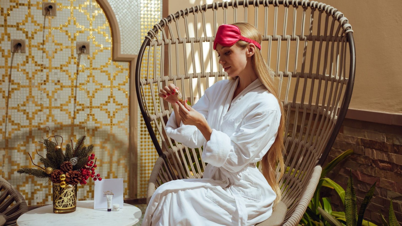 Four-seasons-resort-dubai-festive-spa-wellness-experiences-2026 - travel and tour world Woman enjoying a festive skincare ritual in a luxury spa setting with christmas decorations and golden décor.
