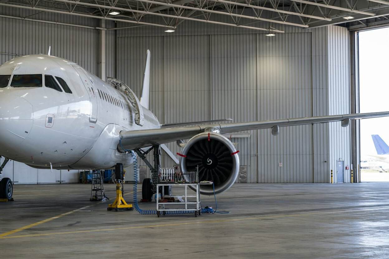 The new airbus forecast from france points to more travel and aviation services demand doubling by 2045 - travel and tour world White passenger aircraft inside a maintenance hangar, with its engine, wing and nearby tools visible