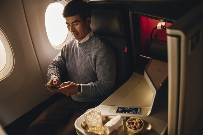Delta - travel and tour world Delta one business class dining featuring a premium wagyu beef burger and macaroni cheese served on an elegant tray table aboard a delta air lines aircraft.