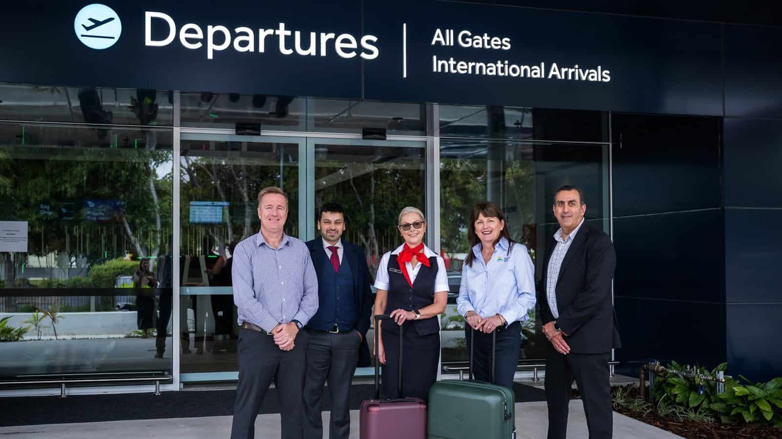 Five people with luggage outside sunshine coast airport departures terminal in queensland, australia.